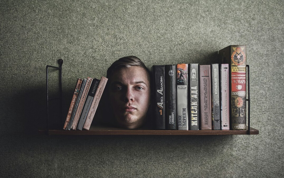 Croatian male novelist with beard sitting by a bookshelf